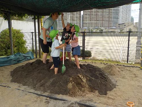 先生と一緒に砂場で山を作って遊んでいます