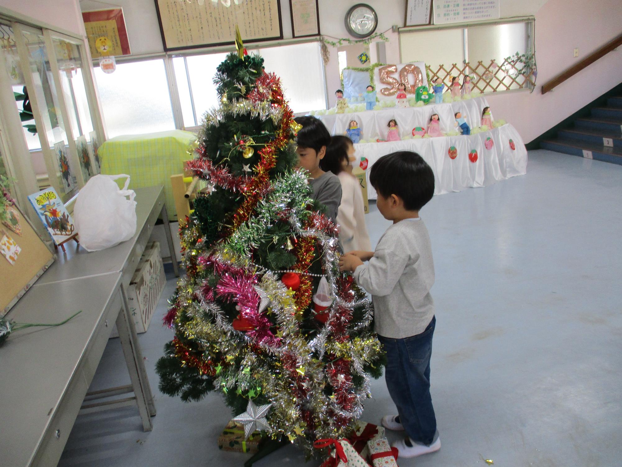 クリスマスツリーに飾りをつけている幼児