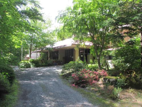 青々と生い茂った木々や植木に囲まれた、朱色の屋根の富士吉田青年の家の建物入り口付近の写真