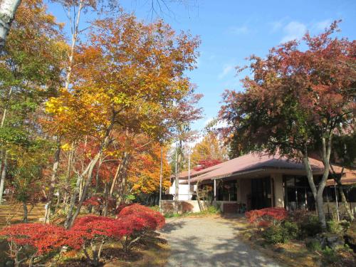 黄色や赤色に染まった木々に囲まれた朱色の屋根の富士吉田青年の家の建物入り口付近の写真