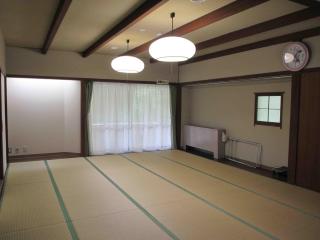 畳の敷かれた広々とした部屋に天井の明かりがついている和室の宿泊室（樹海）の写真