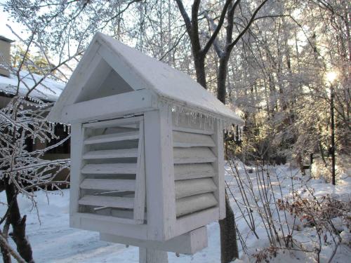 雪が降り積もった三角屋根の木箱の屋根に雨氷が付いている写真