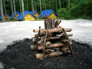 テントから離れた位置に設置された、交互に組んで設置されたキャンプファイヤーの薪の写真