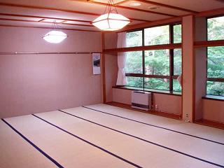 畳の敷かれた和室の右側の窓ガラスから外の景色が見える宿泊室（こぶし）の写真