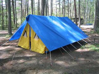 木々が生えているキャンプ場に設置された、青色の屋根のFA型10人用テントの写真