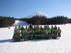 雪が積もった山をバックにスキー場に集まっている子供たちの集合写真